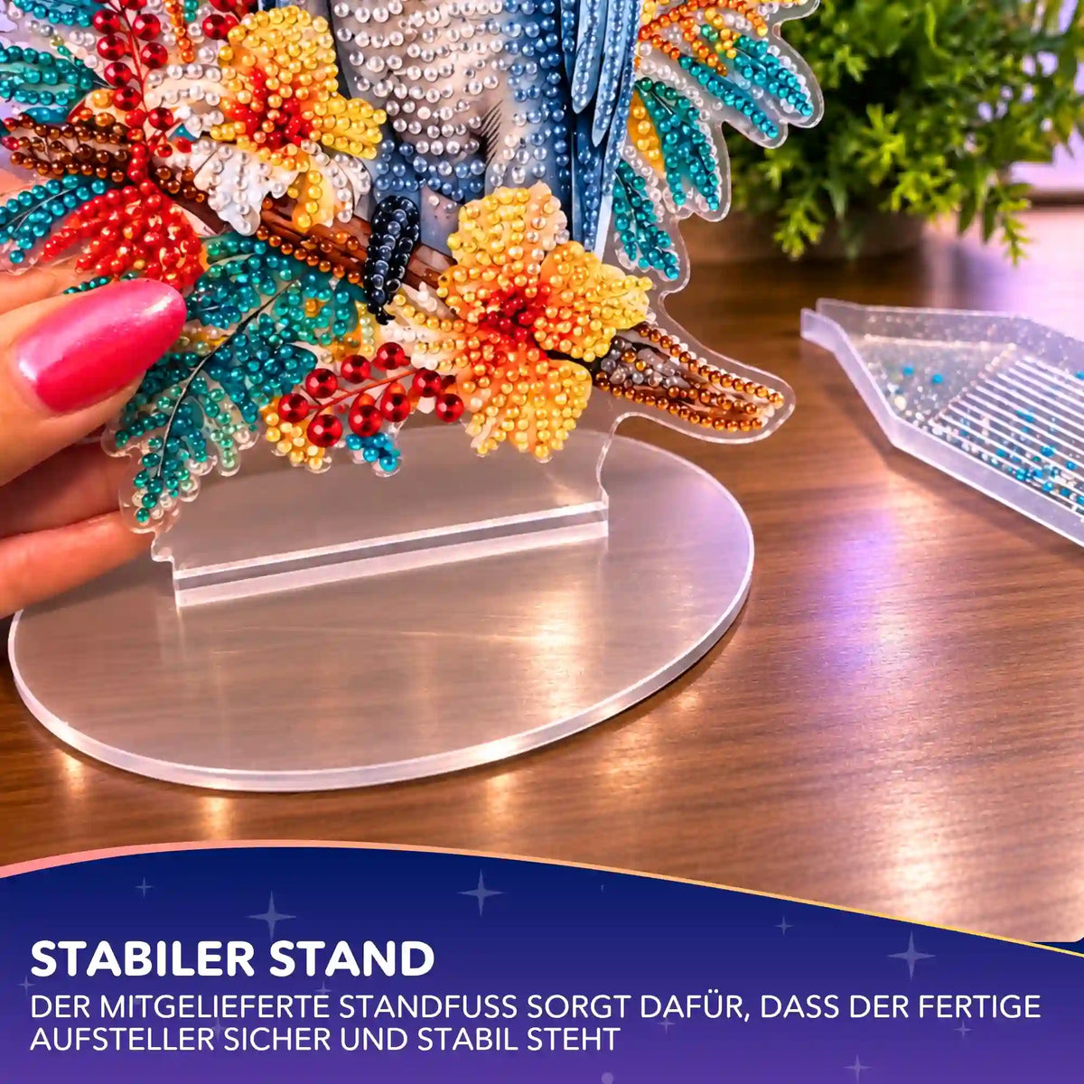 Diamond Painting Aufsteller Kakadu mit bunten Glitzersteinen wird in den stabilen Acryl-Standfuß eingesetzt.