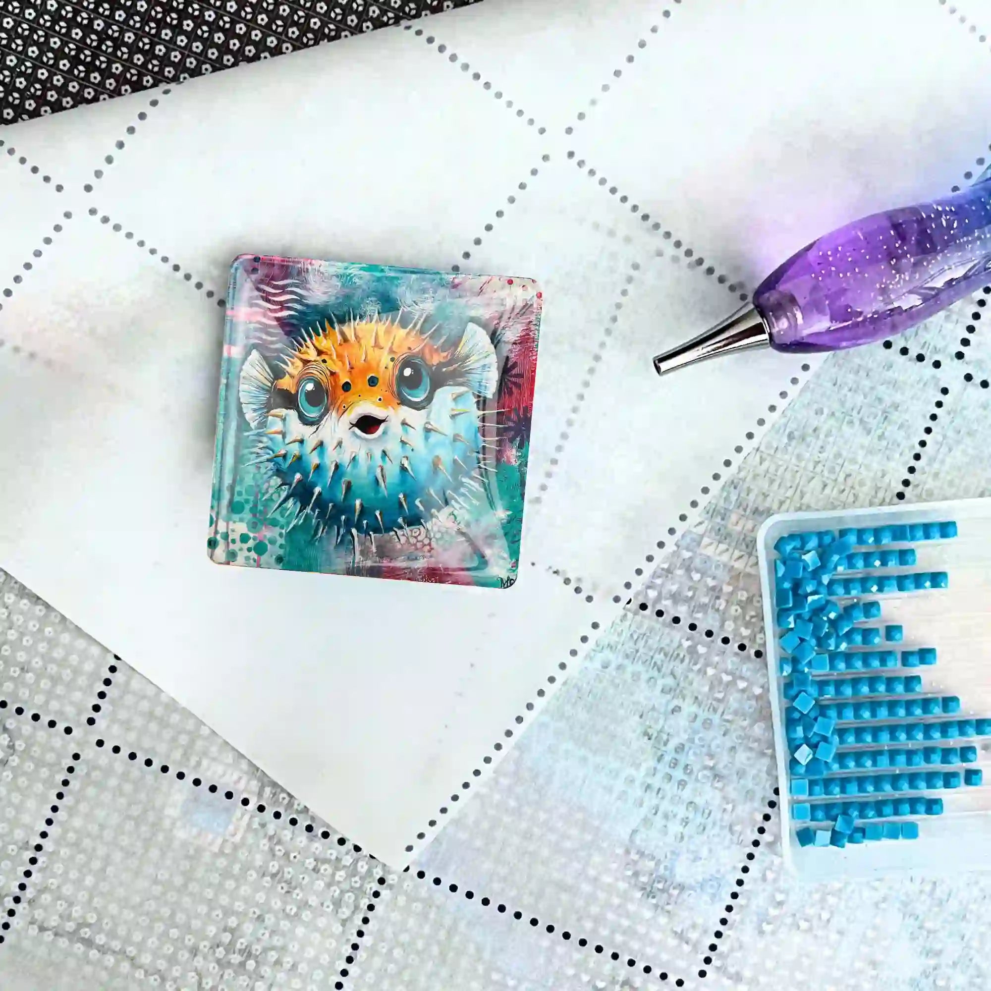 Quadratischer Kugelfisch-Coverminder aus Glas für Diamond Painting auf einer Leinwand mit Stift und blauen Diamanten.