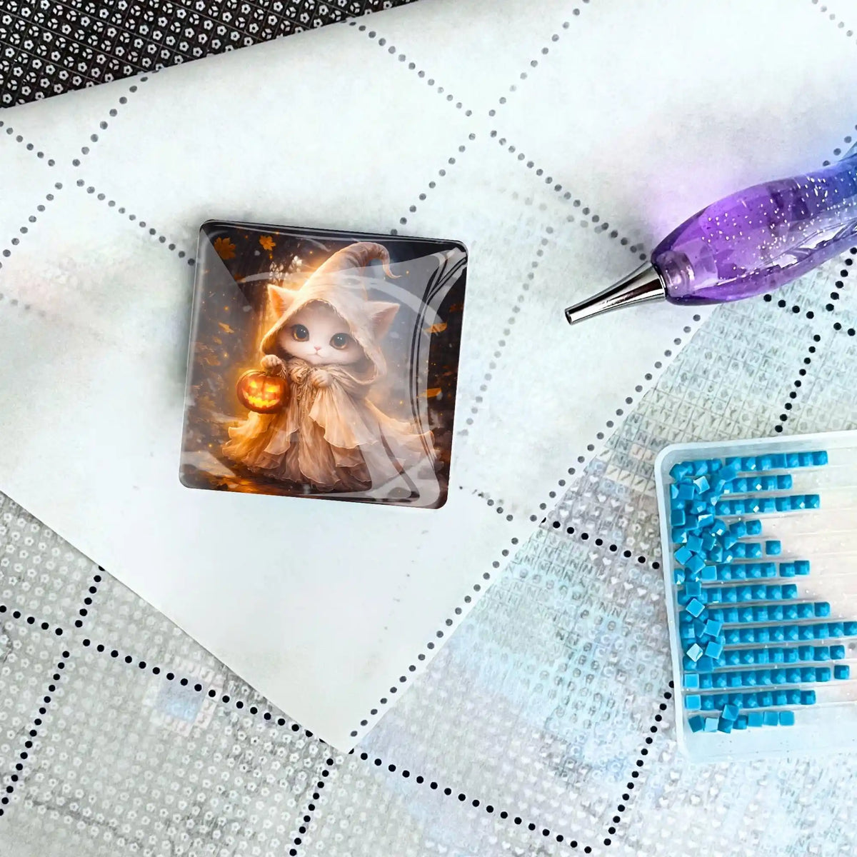 Diamond Painting Cover Minder aus Glas mit Katzen-Motiv hält Abdeckpapier auf Leinwand neben Steinen