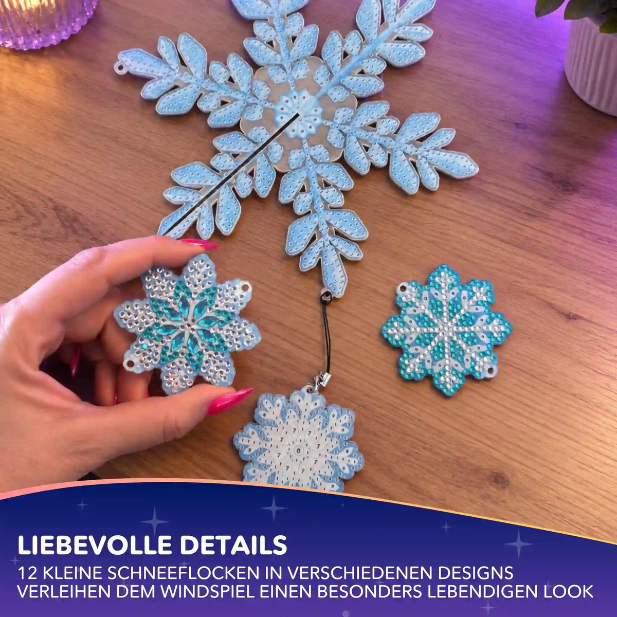 Diamond Painting Windspiel Schneeflocken: Hand hält funkelnden DIY-Anhänger mit blauen Glitzersteinen.