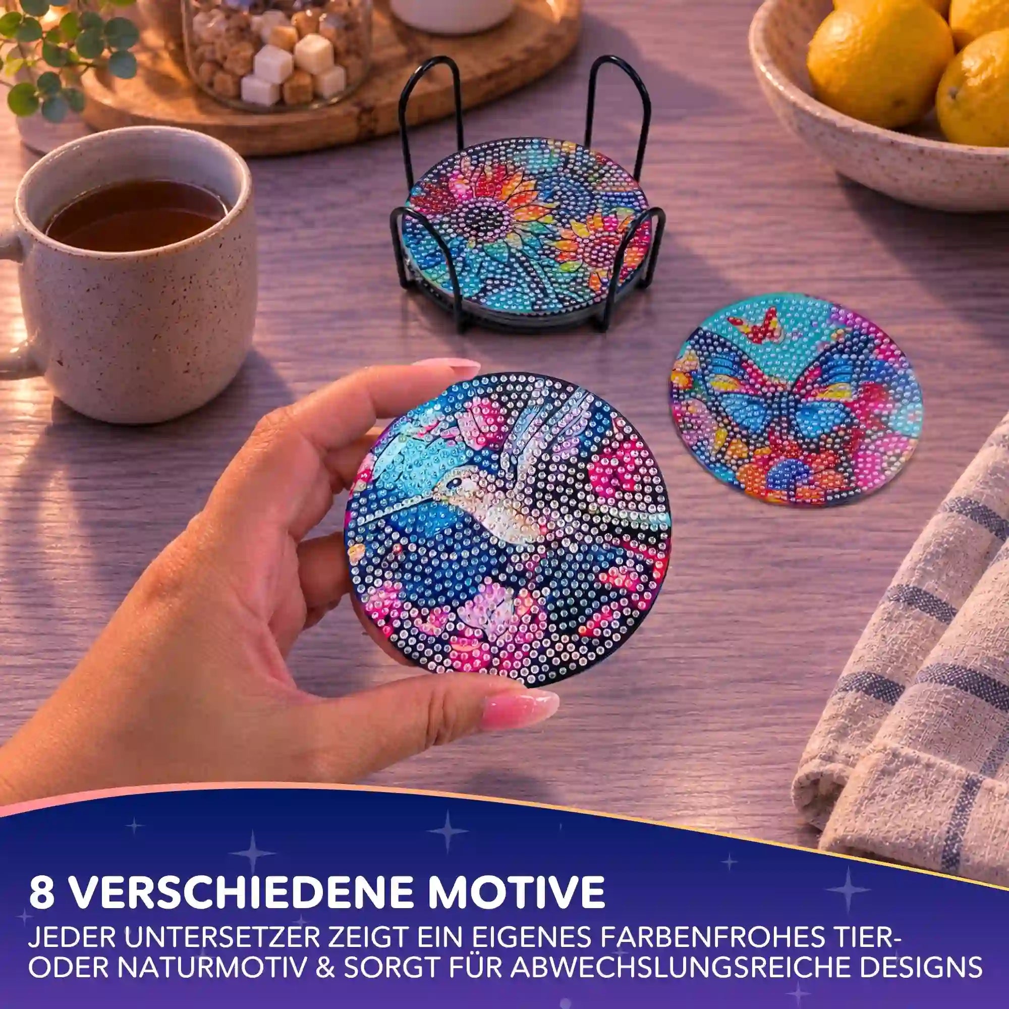 Hand hält bunte Diamond Painting Untersetzer mit Tiermotiven und funkelnden Strass Steinen auf Holztisch