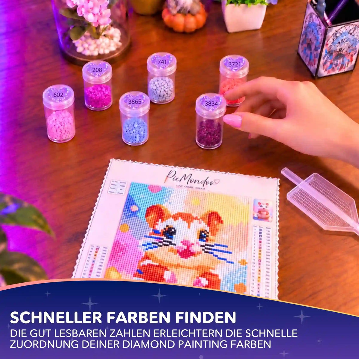 Diamond Painting Herz-Sticker mit DMC-Nummern auf Dosen für Glitzersteine neben Hamster-Leinwand.